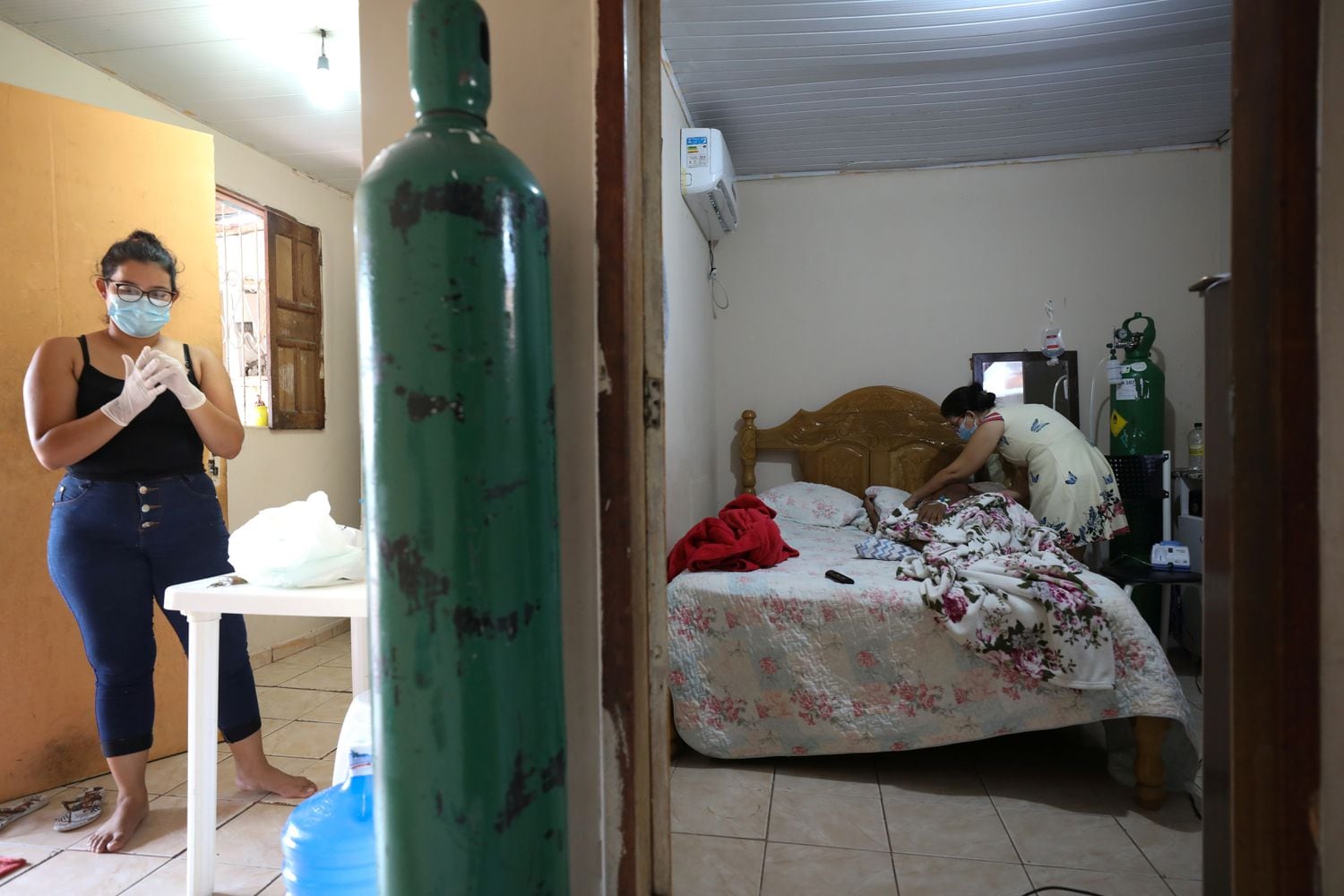 Enfermeira Angela Maria Reis se prepara para tomar conta de Erystenys Reis da Costa, 45, contagiada pela covid-19, em Manaus.