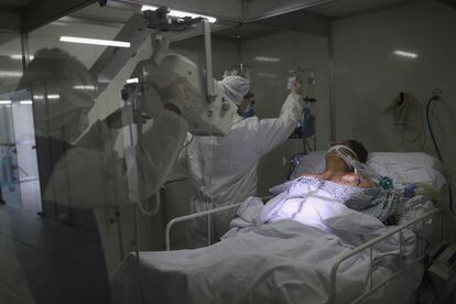 Profissionais da saúde fazem um raio-X do pulmão em um paciente em uma UTI.