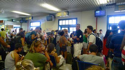 Passageiros esperando em frente às portas de embarque no aeroporto de Santorini.