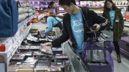 Funcionários com camisetas azuis circulam pela loja coletando em sacolas os pedidos feitos por meio do aplicativo
