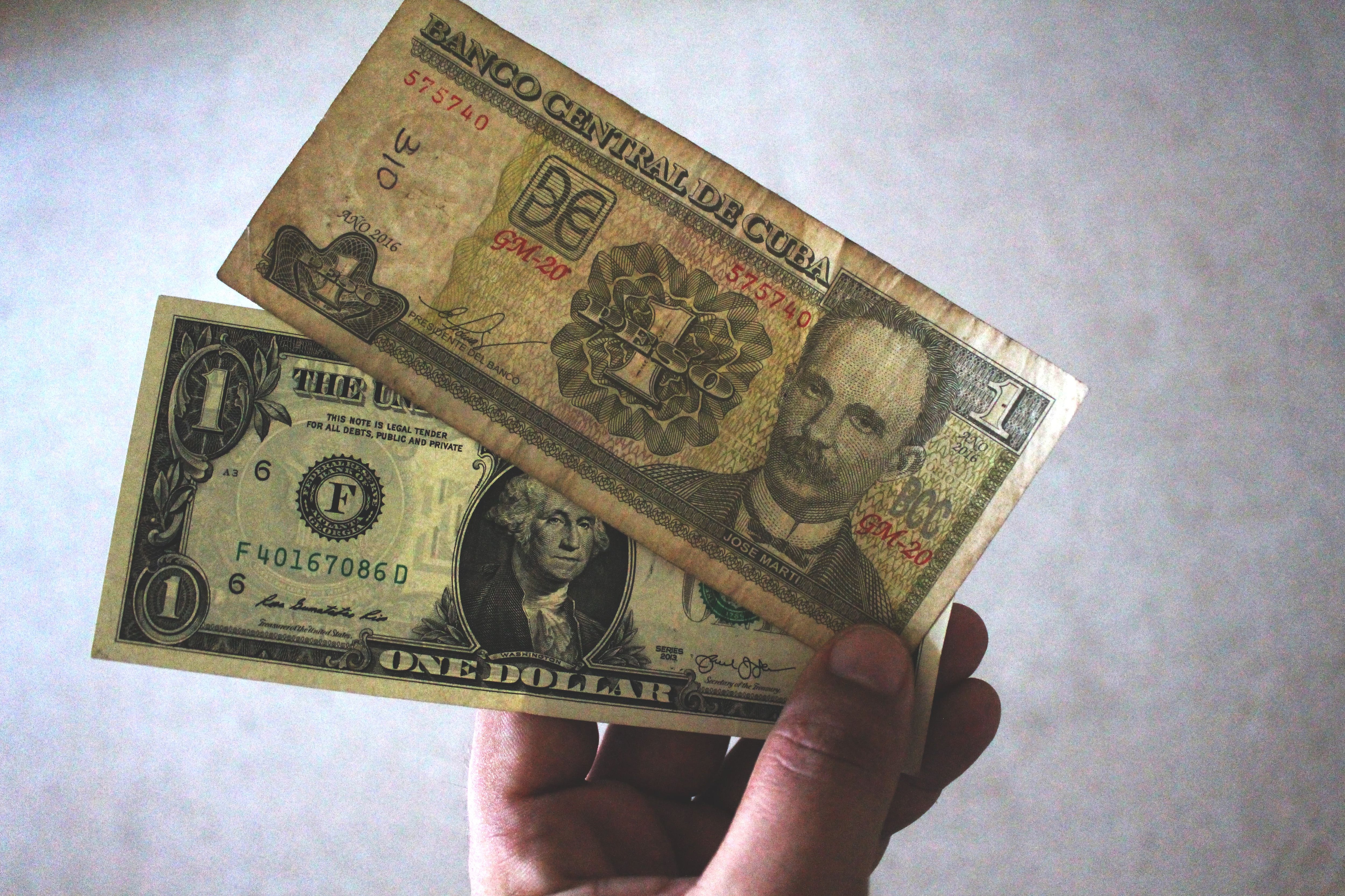 Uma nota de peso cubano com a imagem de José Martí em cima de uma nota de dólar com a imagem de George Washington. O imposto sobre o câmbio do dólar foi abolido em Cuba