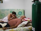 Osmar Magalhaes, 68, who suffers from the coronavirus disease (COVID-19), is helped by his daughter Karoline Magalhaes at his home, where he set up his own emergency ward with air tanks due to lack of oxygen in the public health system, in Manaus, Brazil January 20, 2021. Picture taken January 20, 2021. REUTERS/Bruno Kelly