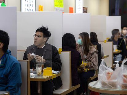 Em um restaurante em Hong Kong as mesas são divididas com uma tela de plástico.