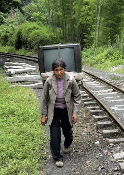 Uma mulher carrega uma televisão em Sichuan.