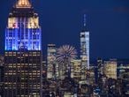 Fireworks explode behind landmark buildings of the Manhattan city skyline including the Empire State building (L) and One World Trade Center (R), illuminated in blue and gold, in celebration of reaching 70 percent of New York adults having received their first dose of the Covid-19 vaccine, in New York on June 15, 2021. (Photo by Ed JONES / AFP)