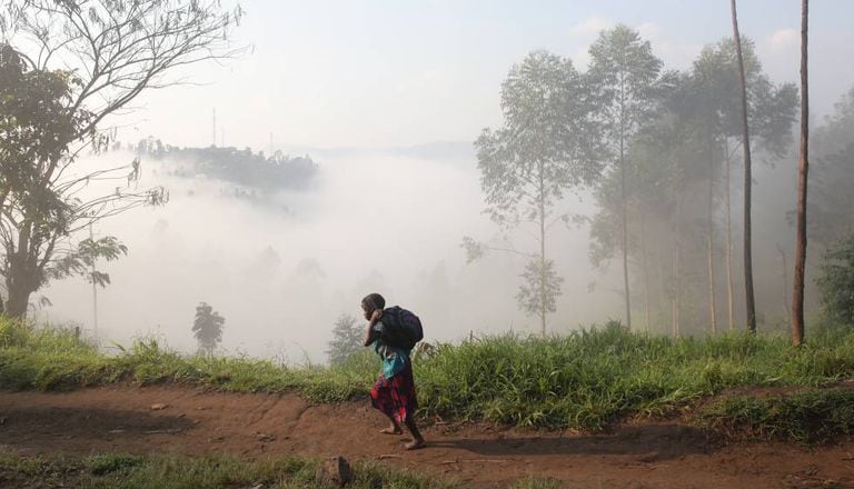 Uma criança vai para a escola levando sua mochila no Congo.