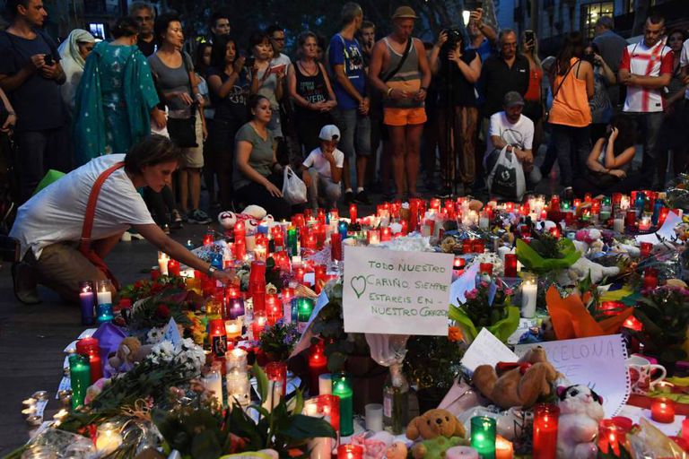 Pessoas deixam flores e velas em homenagens às vítimas em Las Ramblas.