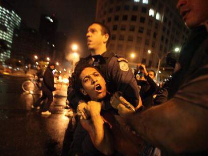 Um policial prende um manifestante terça-feira no Rio.