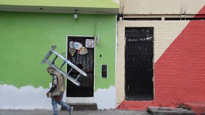 Um pintor de paredes caminha com uma escada nas costas enquanto trabalha nas fachadas das casas de San Cristóbal, em 18 de agosto passado, em Lima.