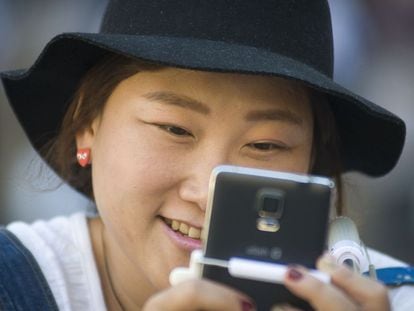Uma turista asiática olha seu telefone celular.