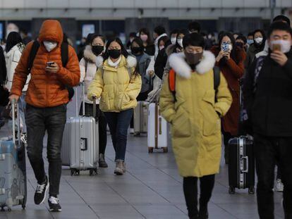 Um grupo de pessoas com máscara deixa uma estação ferroviária de Pequim, neste sábado.