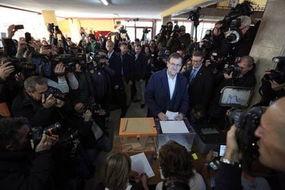 O premi&ecirc; Mariano Rajoy vota neste domingo, cercado por jornalistas.