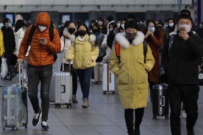 Um grupo de pessoas com máscara deixa uma estação ferroviária de Pequim, neste sábado.