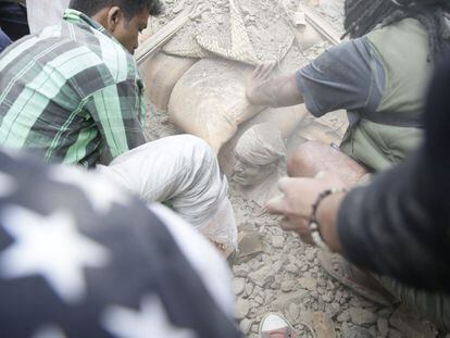 Um homem soterrado entre as ruínas de um edifício em Katmandu.