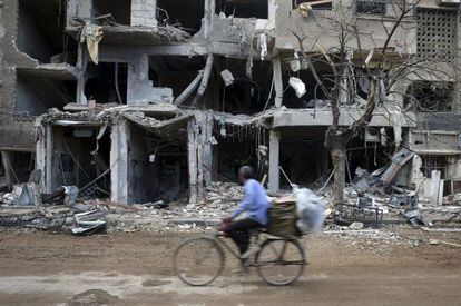 Um homem passa diante de edifícios destruídos em um subúrbio de Damasco.