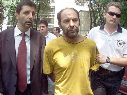 O líder dos sequestradores do publicitário Washington Olivetto, o chileno Maurício Hernandez Norambuena (c), é levado preso por policiais para ser apresentado na Delegacia Antissequestro (DEAS), em São Paulo, no dia 4 de fevereiro de 2002.
