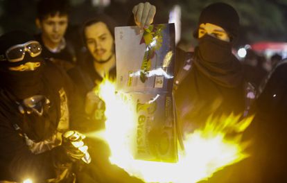 Manifestantes queimam um álbum de figurinhas da Copa.