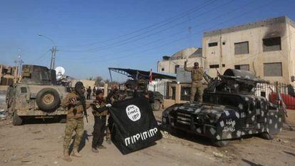 Forças iraquianas mostram vitoriosas uma bandeira do ISIS depois de recuperar Ramadi.