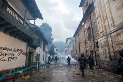Integrantes do Esquadrão Móvel Antidistúrbios jogam gases e caminham entre escombros após confrontos na Praça Bolivar quando homens encapuzados tentam entrar na Prefeitura de Bogotá.