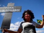 An activist from Black Coalition for Rights, which represents Brazilian Black movements, holds a cross in tribute to the coronavirus disease (COVID-19) victims, in front of the National Congress after delivering a formal request of impeachment against Brazil's President Jair Bolsonaro, in Brasilia, Brazil August 12, 2020. The writing reads, "Bolsonaro out". REUTERS/Adriano Machado