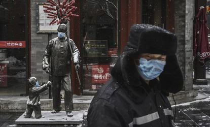 Estátuas cobertas com máscaras em uma rua de Pequim com os estabelecimentos fechados.