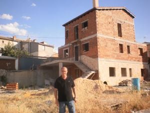 O prefeito de Olmeda da Encosta (Cuenca), José Luis Regacho, posa adiante de uma das parcelas leiloadas, onde seu novo dono já se está construindo uma casa.