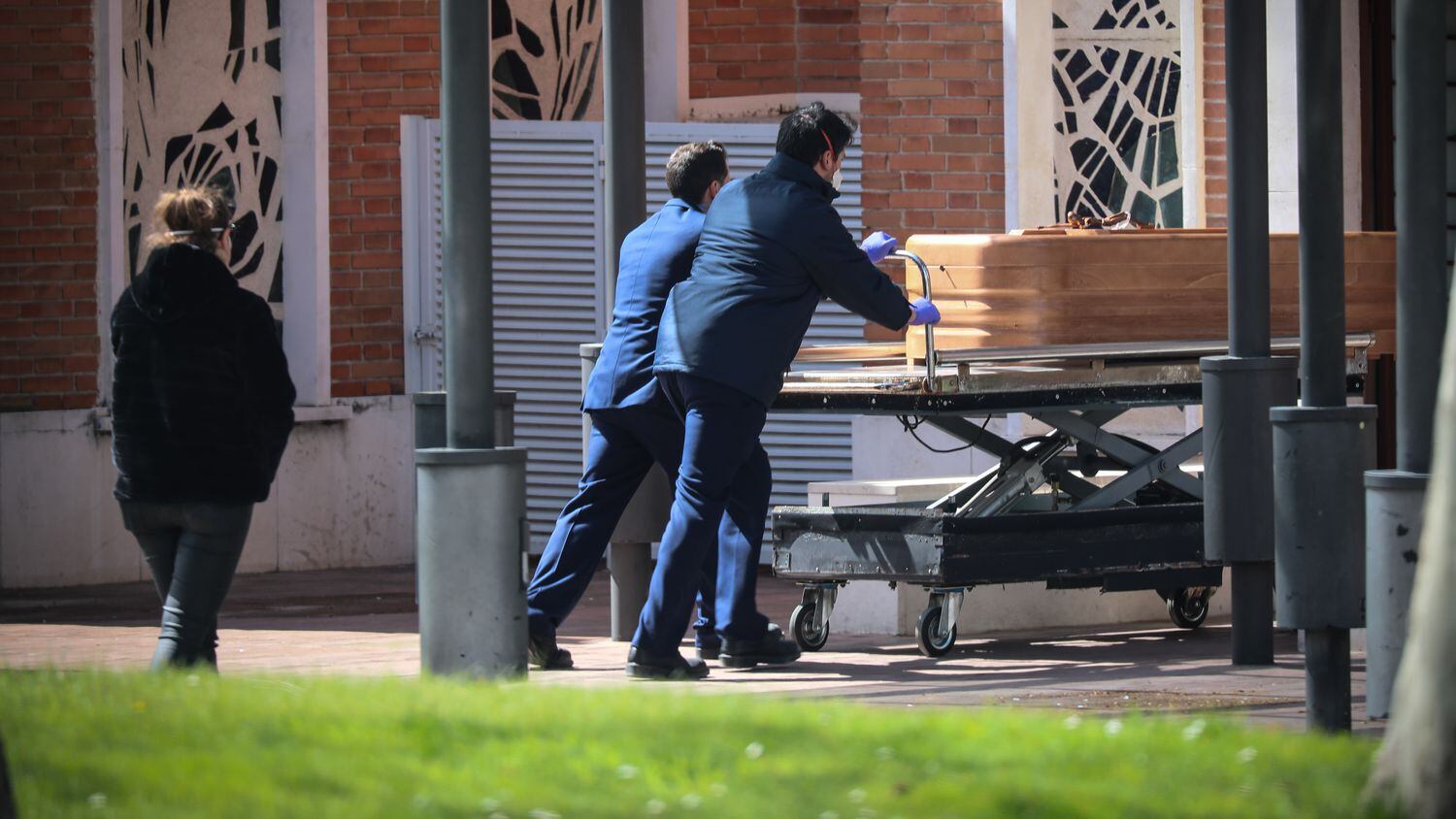 Dois trabalhadores levam um caixão no cemitério de La Almudena, em Madri, em março.