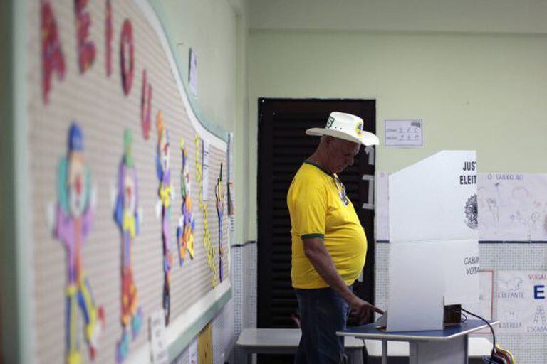 Um homem com camiseta amarela vota em uma escola em Brasília.