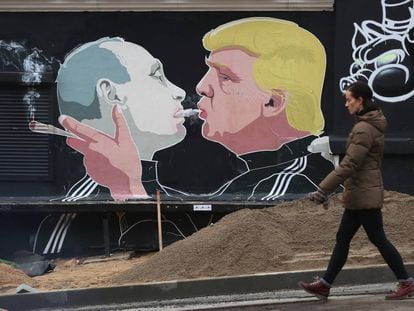 Uma mulher ao lado de um mural com a imagem de Trump e Putin em Vilnius, na Lituânia.