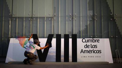 Mulher limpa o logotipo da Cúpula das Américas em Lima