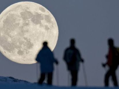Três praticantes de esqui de montanha contemplam a lua cheia em Weissfluhjoch, em Arosa (Suíça), um dia antes do solstício de inverno.