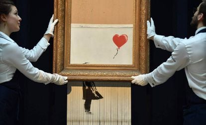 Empregados da Sotheby’s carregam a obra semidestruída de Banksy.