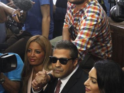 Os presos Mohamed Fahmy (centro) e Baher Mohamed (de pé, acima) falam com a imprensa ao lado da advogada Amal Clooney (direita) e da mulher de Fahmy.