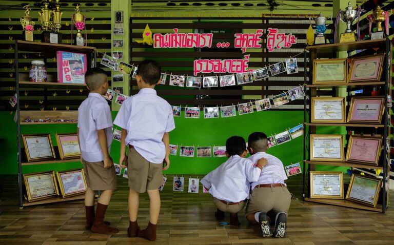 Colegas de um dos meninos presos na caverna de Tham Luang (Tailândia) lhe prestam homenagem na entrada da escola nesta segunda-feira.