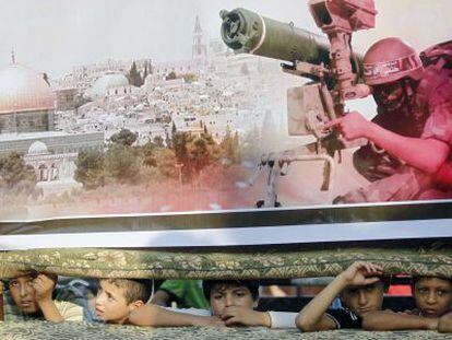 Garotos em Rafah debaixo de um cartaz do Hamas.