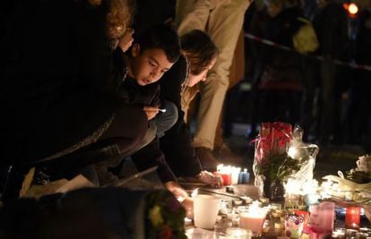 Um grupo de pessoas, entre elas um menino, colocam flores e velas nas proximidades da sala Bataclan, em Paris, um dos cenários dos ataques jihadistas cometidos na noite de 13 de novembro de 2015.