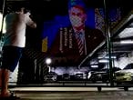 An image of Brazil's President Jair Bolsonaro wearing a protective face mask and the phrase �Hysteria Damages the Economy" is projected on the wall of a building as a protest against the president regarding his handling of the coronavirus COVID-19 outbreak, in Sao Paulo, Brazil, March 21, 2020. - An estimated 900 million people are now confined to their homes in 35 countries around the world -- including 600 million hemmed in by obligatory government lockdown orders -- according to an AFP tally on March 21 at 1900 GMT based on official sources. (Photo by Miguel SCHINCARIOL / AFP)
