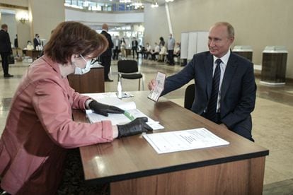 Putin mostra seu passaporte antes de votar, nesta quarta-feira, em uma seção eleitoral de Moscou.