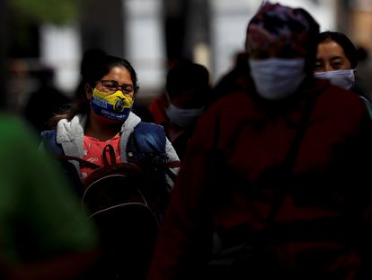 Várias pessoas com máscaras caminham por uma rua de Quito, em 25 de agosto.
