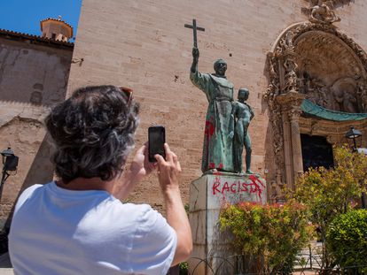 Un hombre fotografía una pintada crítica en el monumento dedicado al fraile Junípero Serra en Palma