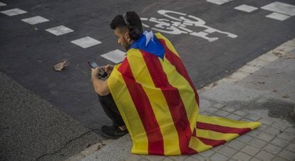 Um jovem sentado com uma bandeira da Catalunha em Barcelona nesta quinta. 