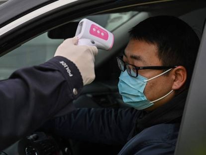 Policial mede a temperatura de motorista em Wuhan, epicentro do surto do coronavírus na China.