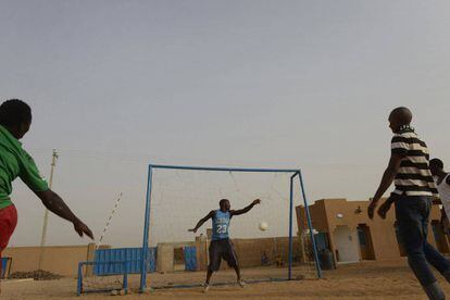 Migrantes jogam futebol no pátio central de um centro de acolhida da OIM.