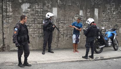 Policiais militares revistam um jovem em uma favela do Rio de Janeiro.