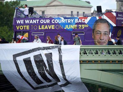 Um ônibus com propaganda em favor da saída da UE passa por trás de partidários da permanência.