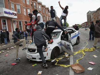 Manifestantes de Baltimore destroem um carro de pol&iacute;cia. 