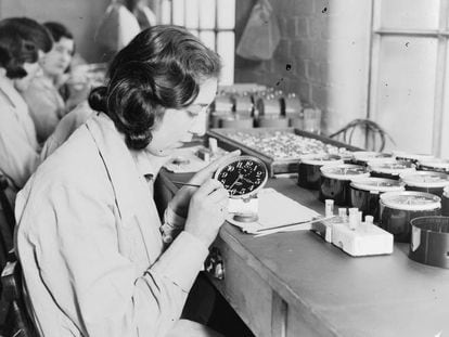 Uma trabalhadora emprega pintura luminosa em uma fábrica de relógios em 1932.