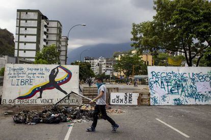 Jovem caminha em frente a uma barricada em Caracas.