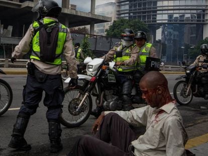 Homem ferido junto a policiais da Guarda Nacional Bolivariana.