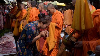 Uma mulher diante de monges budistas no Camboja.